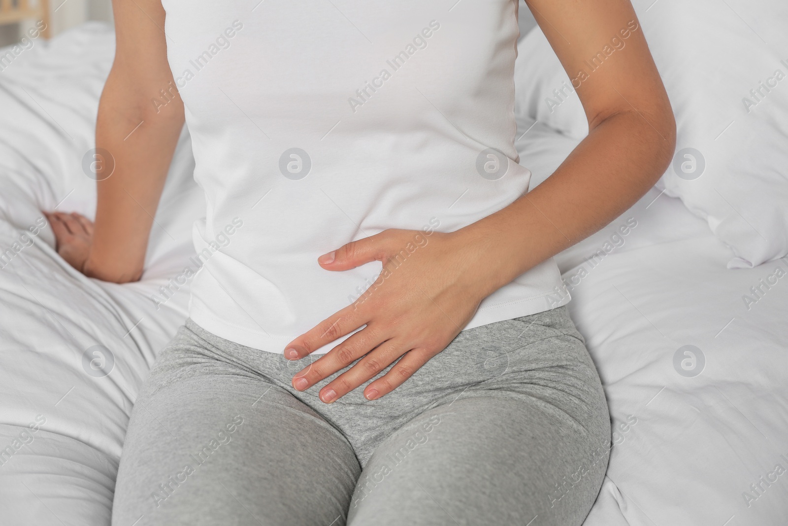 Photo of Young woman suffering from cystitis on bed, closeup