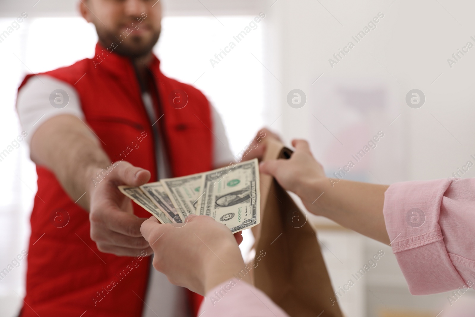 Photo of Young deliveryman receiving tips from woman indoors, closeup