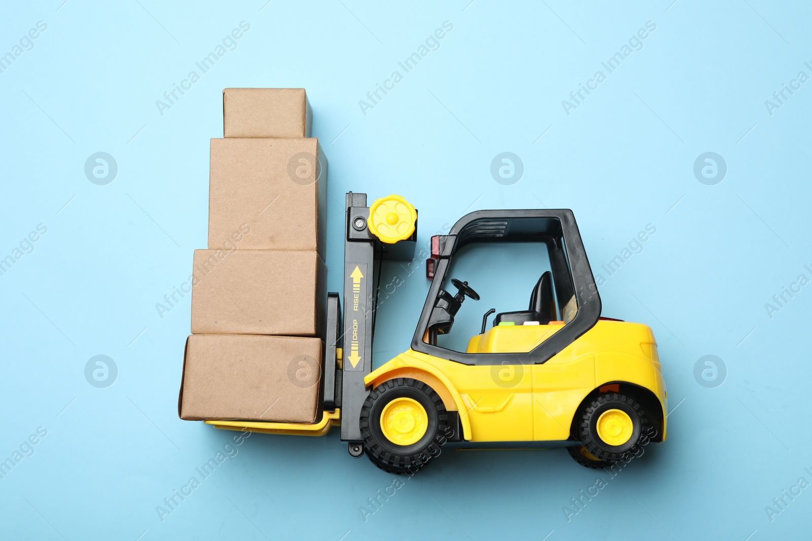 Photo of Top view of toy forklift with boxes on blue background, space for text. Logistics and wholesale concept