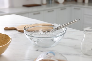 Whisk, bowl, board and pitcher on white marble table indoors