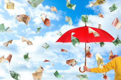 Image of Woman holding umbrella under money rain and blue sky on background, closeup 