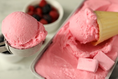 Delicious ice cream in container and wafer cone on table, closeup