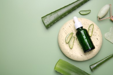 Photo of Flat lay composition with cosmetic products and cut aloe leaves on pale green background. Space for text