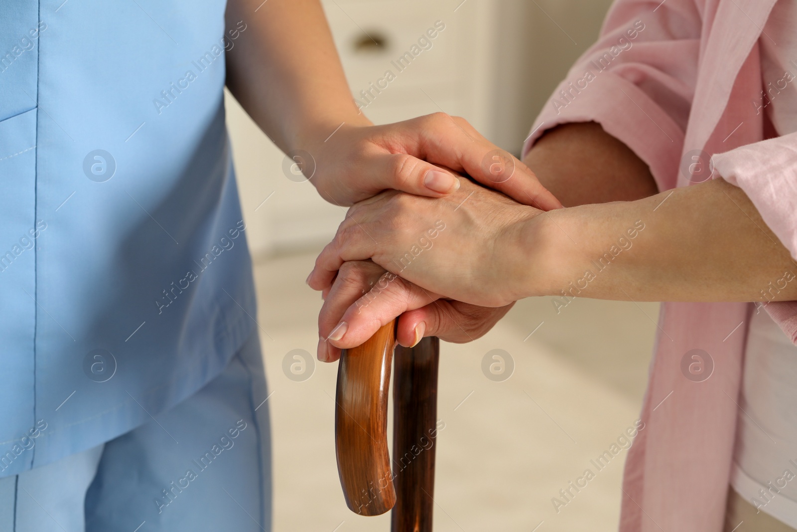 Photo of Elderly woman with walking cane and female caregiver indoors, closeup