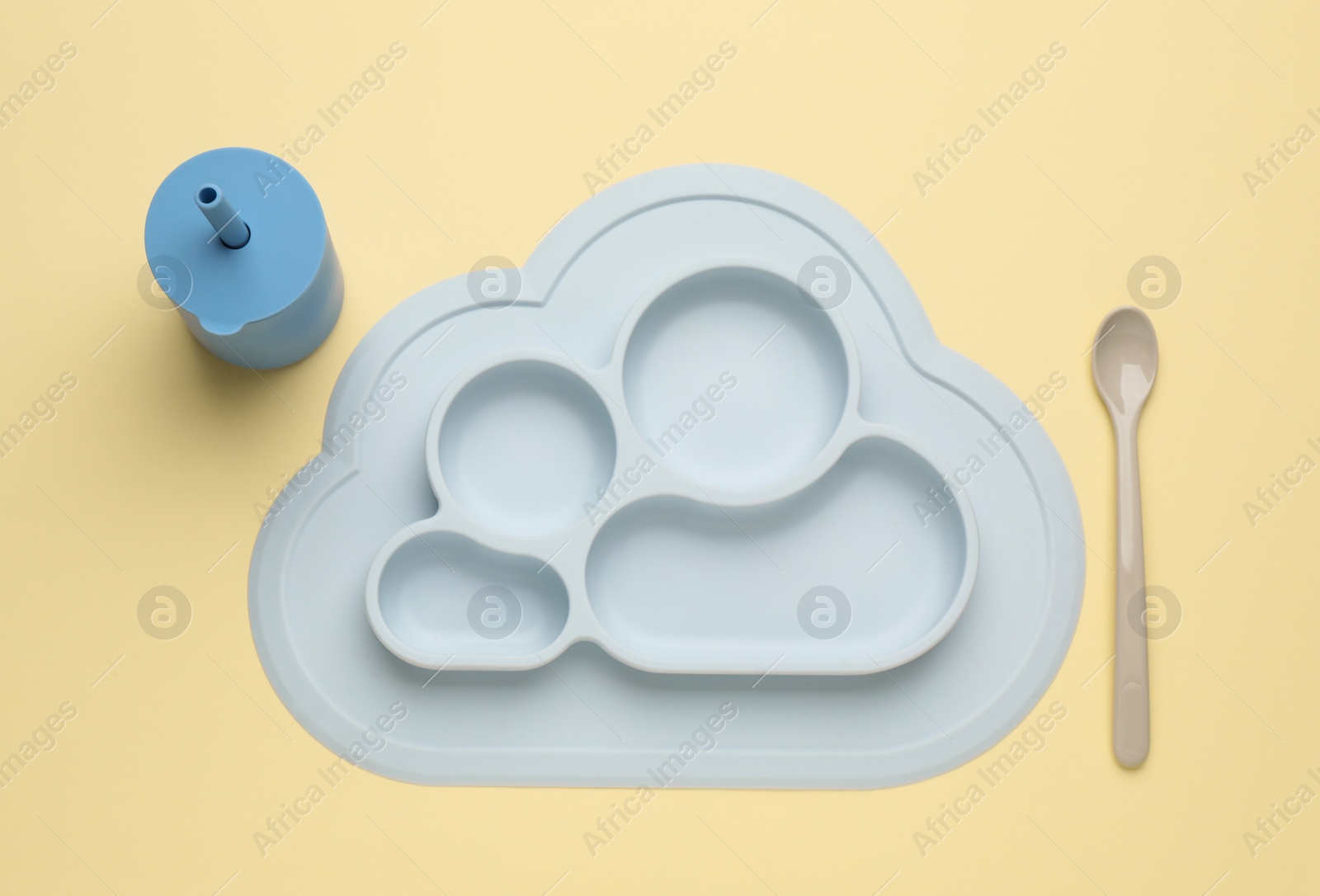 Photo of Set of plastic dishware on beige background, flat lay. Serving baby food