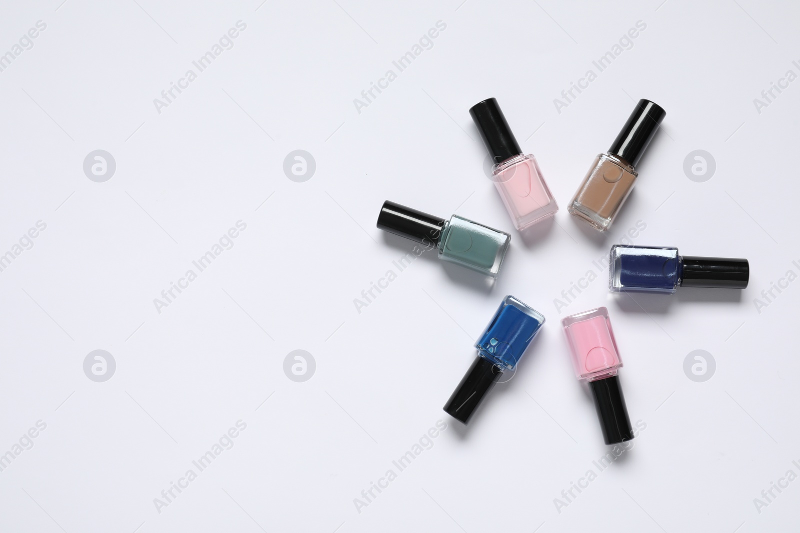 Photo of Nail polishes on white background, flat lay. Space for text