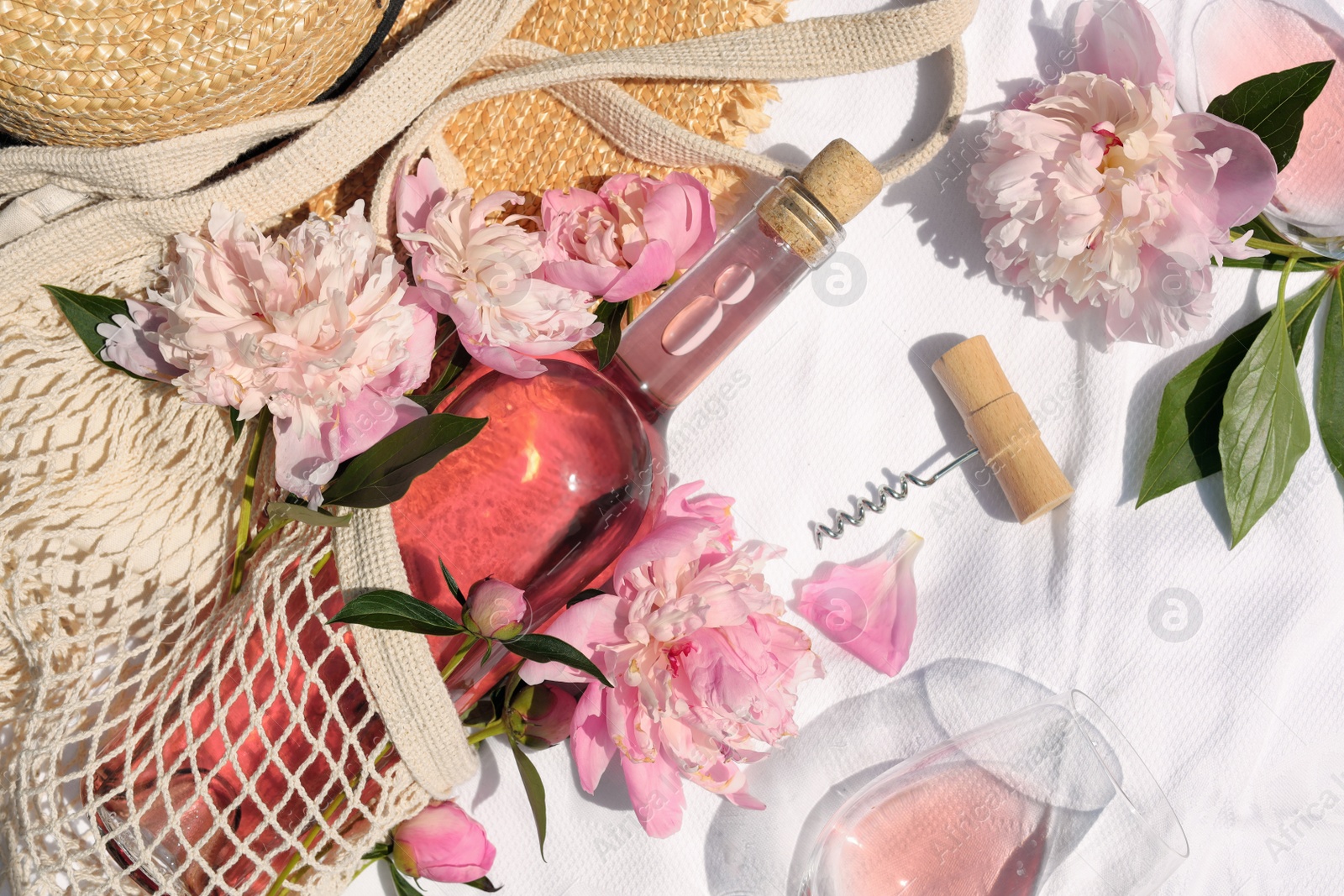 Photo of Flat lay composition with beautiful peonies and rose wine on white fabric