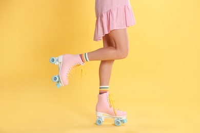 Photo of Young woman with retro roller skates on color background, closeup