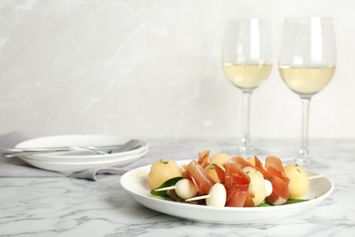 Photo of Melon, mozzarella and prosciutto skewers served on marble table. Space for text