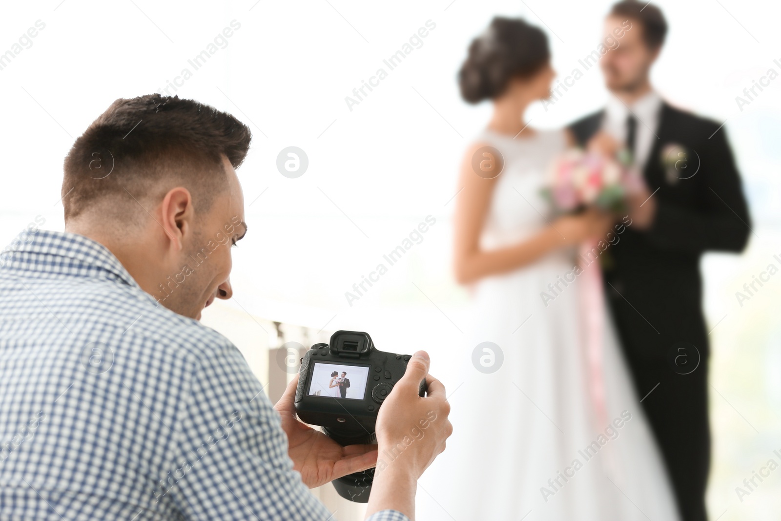 Photo of Professional photographer with camera and wedding couple in studio