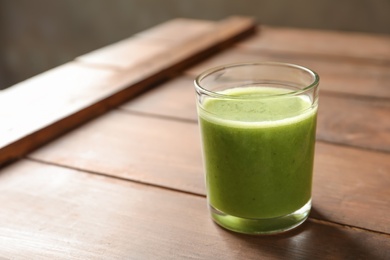 Photo of Glass with delicious detox juice on wooden table