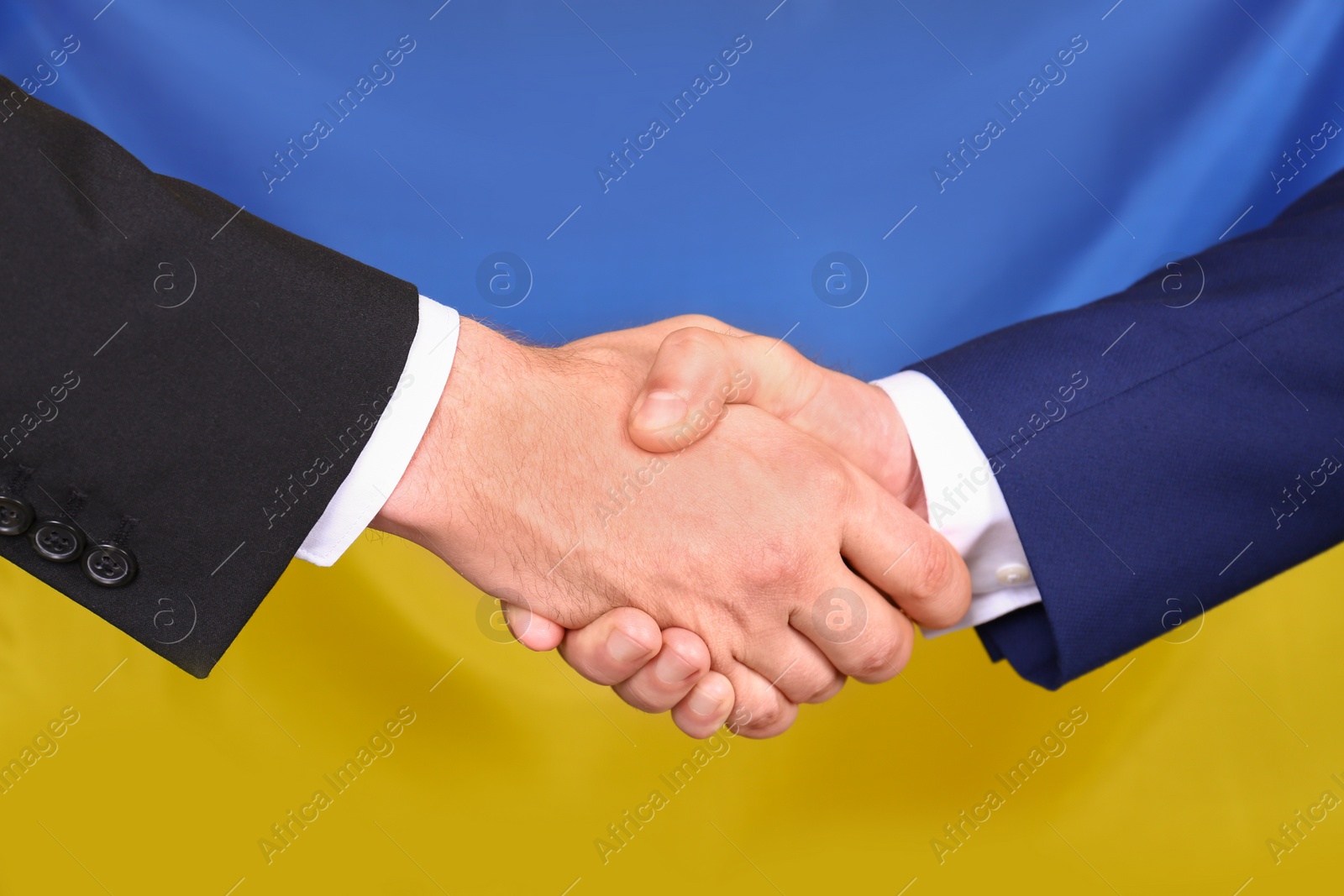 Photo of Men shaking hands against Ukrainian national flag, closeup. International relationships