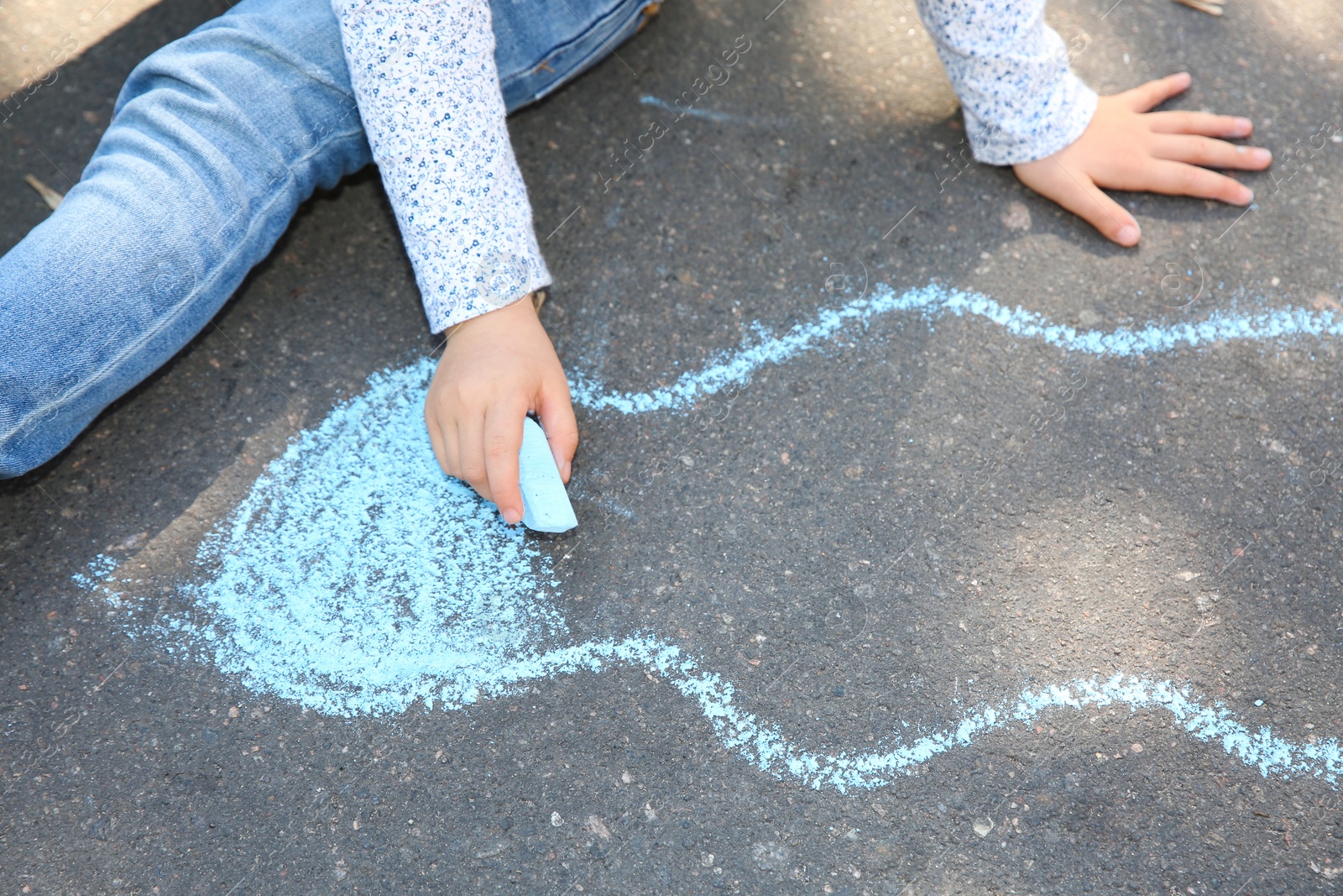 Photo of Little child drawing with colorful chalk on asphalt, closeup