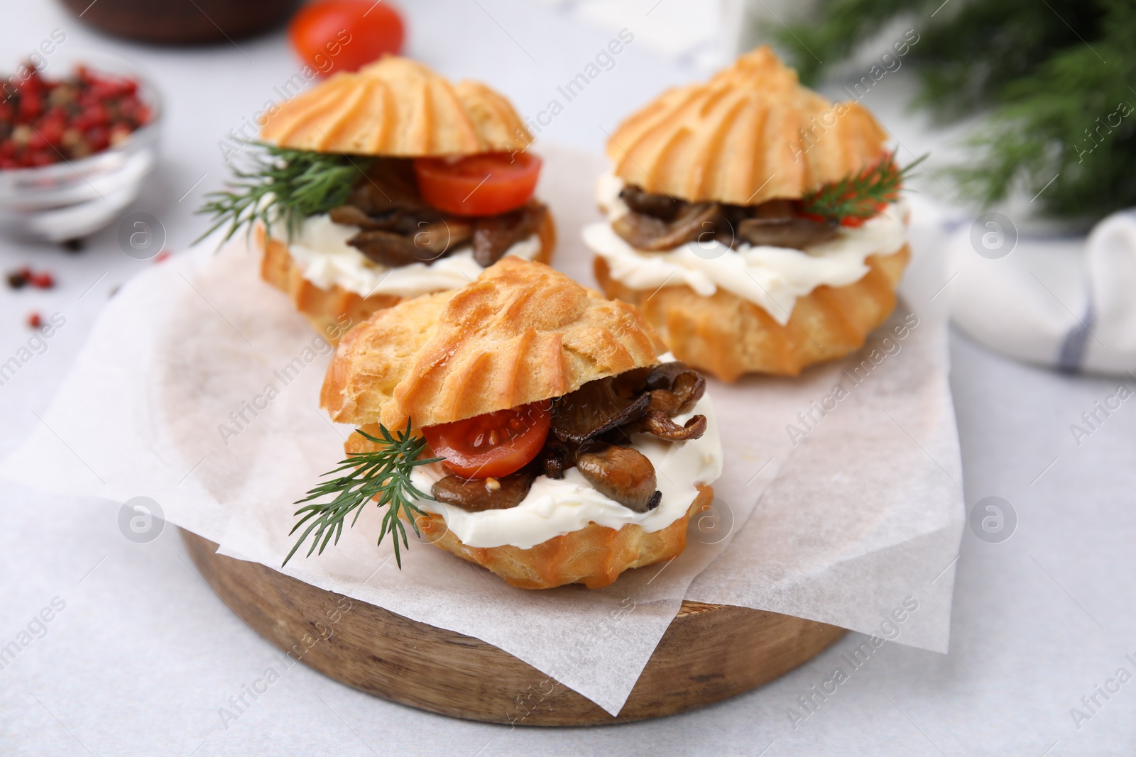 Photo of Delicious profiteroles with cream cheese, mushrooms, tomato and dill on white table, closeup