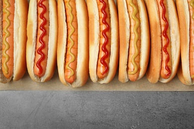 Photo of Tasty fresh hot dogs on grey background, top view