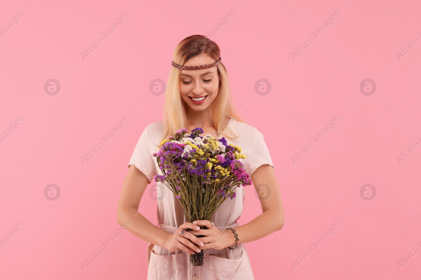 Photo of Portrait of smiling hippie woman with bouquet of flowers on pink background