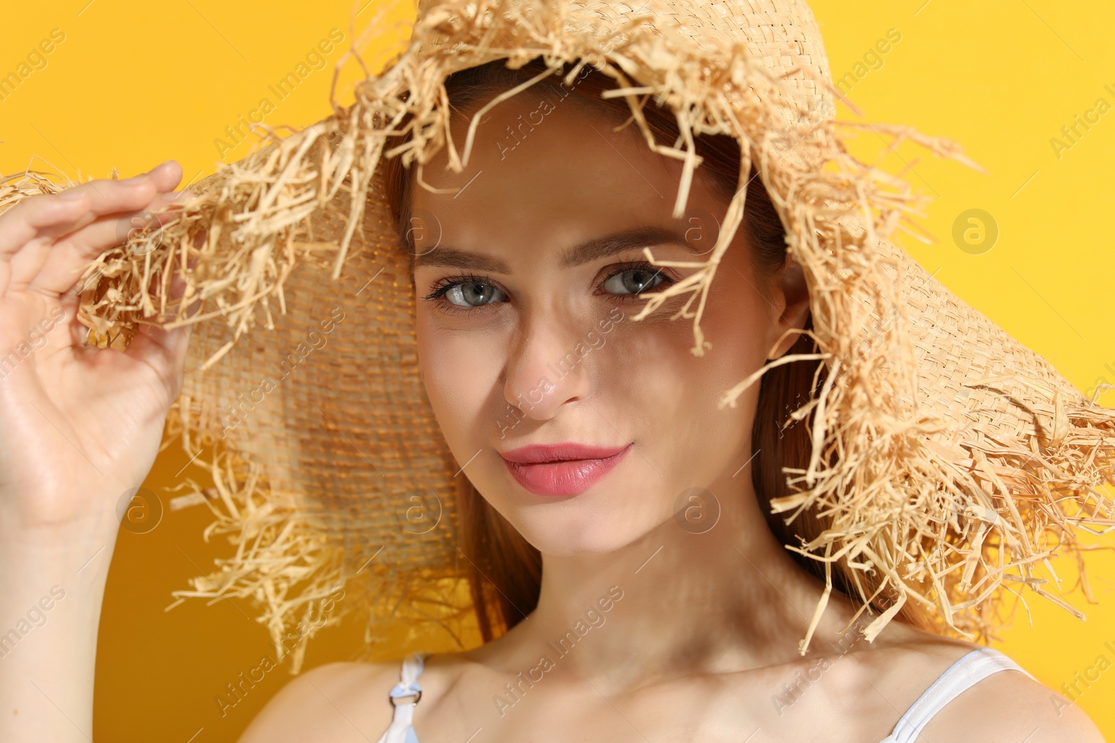 Photo of Beautiful young woman in straw hat on orange background