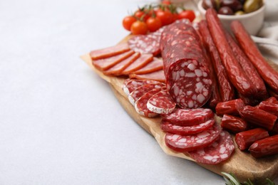 Photo of Different types of delicious sausages and ingredients on light grey table, closeup. Space for text