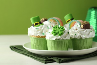 St. Patrick's day party. Tasty festively decorated cupcakes on white table, closeup