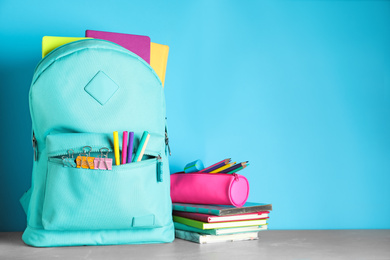 Photo of Stylish backpack with different school stationery on table against light blue background. Space for text