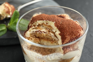 Photo of Delicious tiramisu in glass on table, closeup