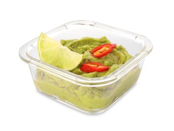 Photo of Bowl of delicious guacamole with chili pepper and lime isolated on white