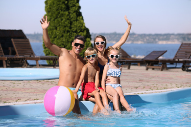 Photo of Happy family with inflatable ball at poolside on sunny summer day