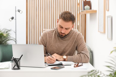 Young man working with laptop at home