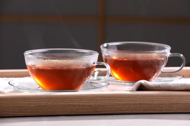 Photo of Aromatic hot tea in glass cups on light table indoors