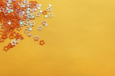 Photo of Shiny bright star shaped glitter on pale orange background. Space for text