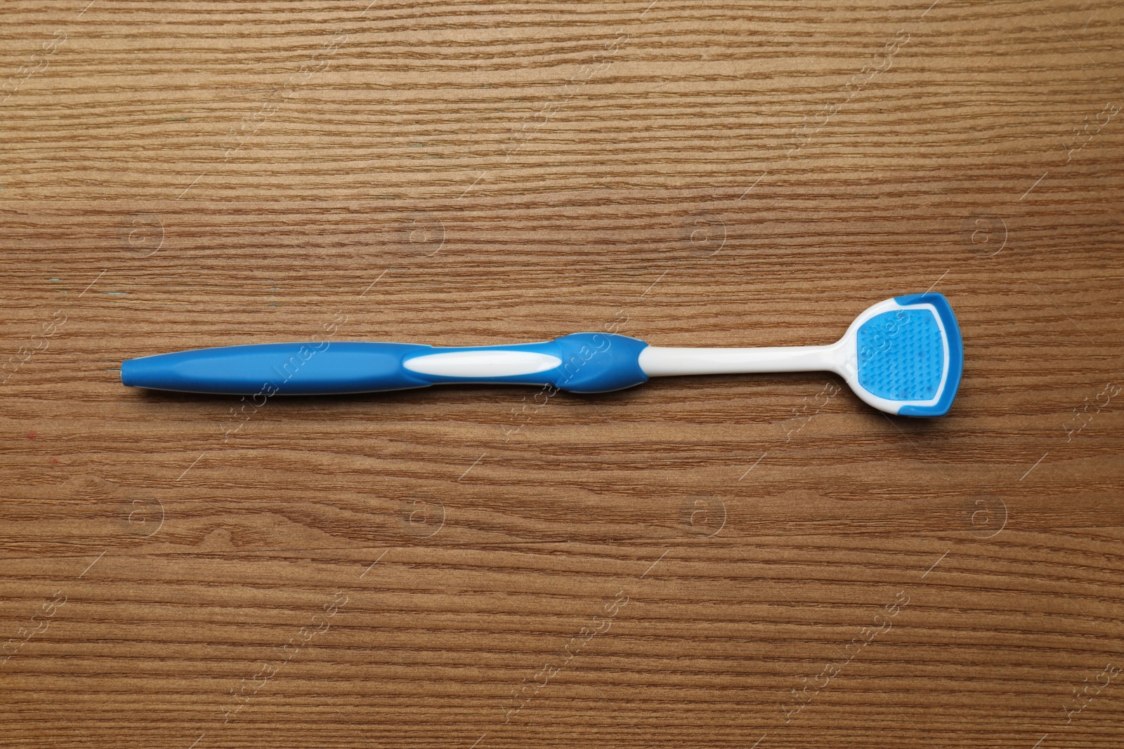 Photo of Blue tongue cleaner on wooden table, top view