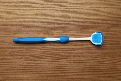 Photo of Blue tongue cleaner on wooden table, top view