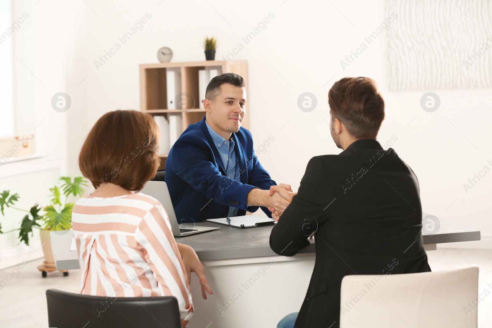 Photo of Human resources manager shaking hands with applicant before job interview in office