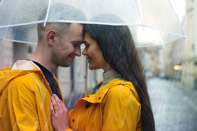 Image of Lovely young couple with umbrella under rain on city street