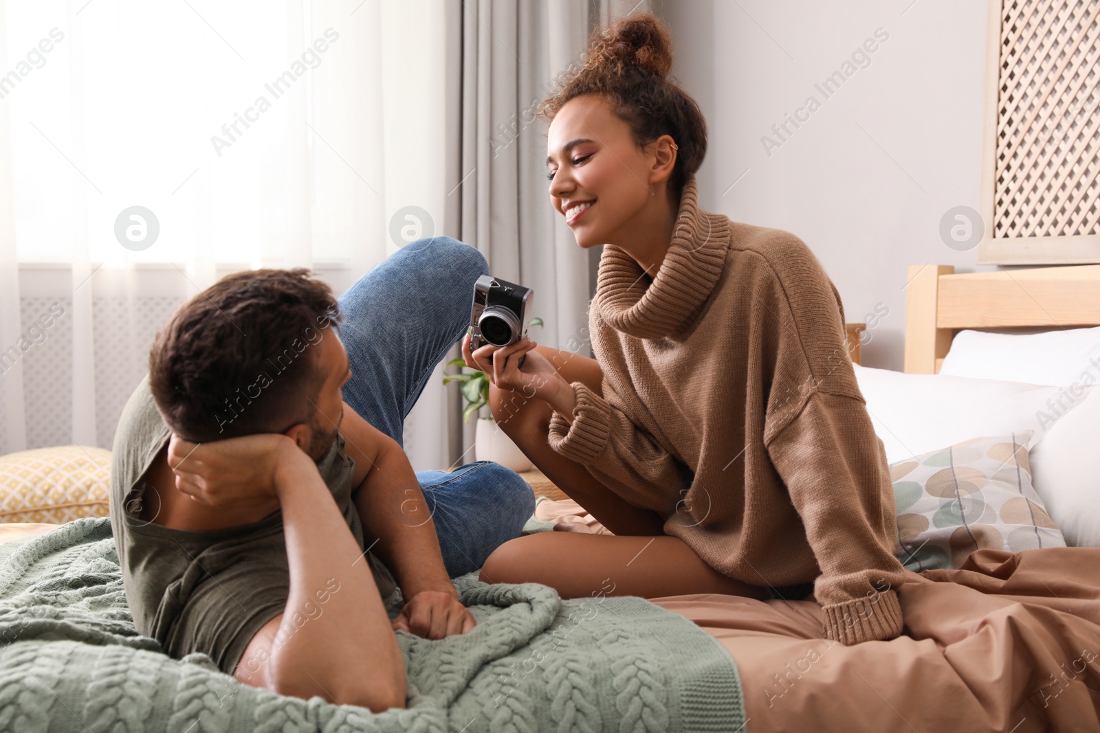 Photo of Lovely couple with camera on bed at home