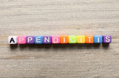 Photo of Word Appendicitis made of color cubes with letters on wooden table, top view