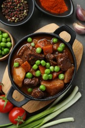 Photo of Delicious beef stew and ingredients on grey table, flat lay