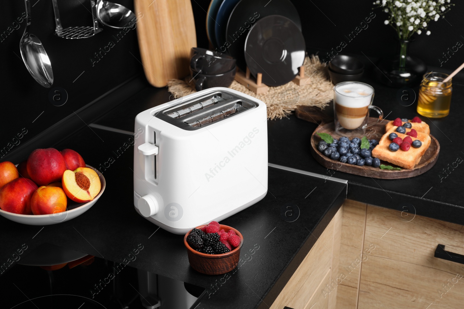 Photo of Modern toaster, bread with fresh berries and coffee on countertop in kitchen