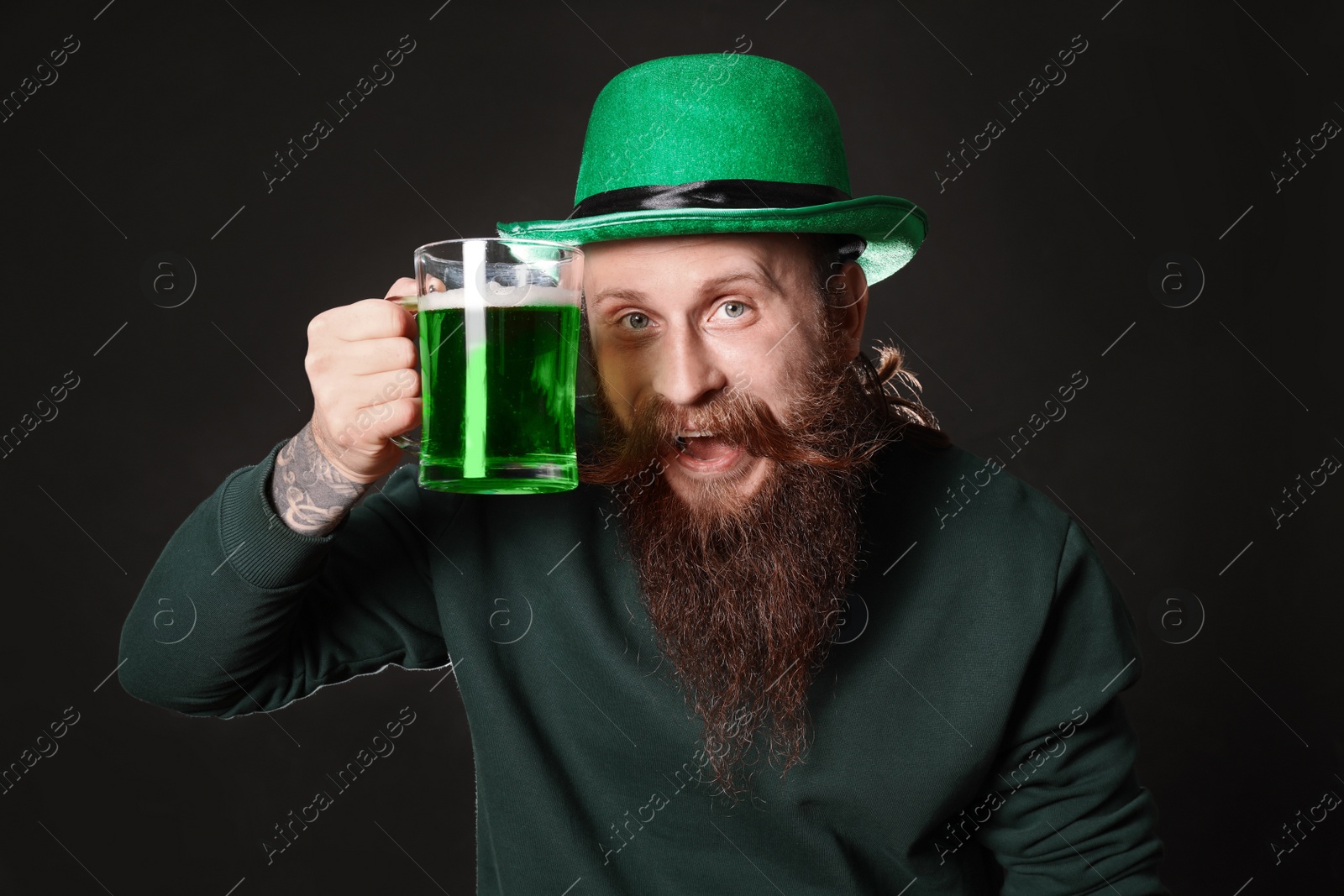 Photo of Bearded man with green beer on black background. St. Patrick's Day celebration
