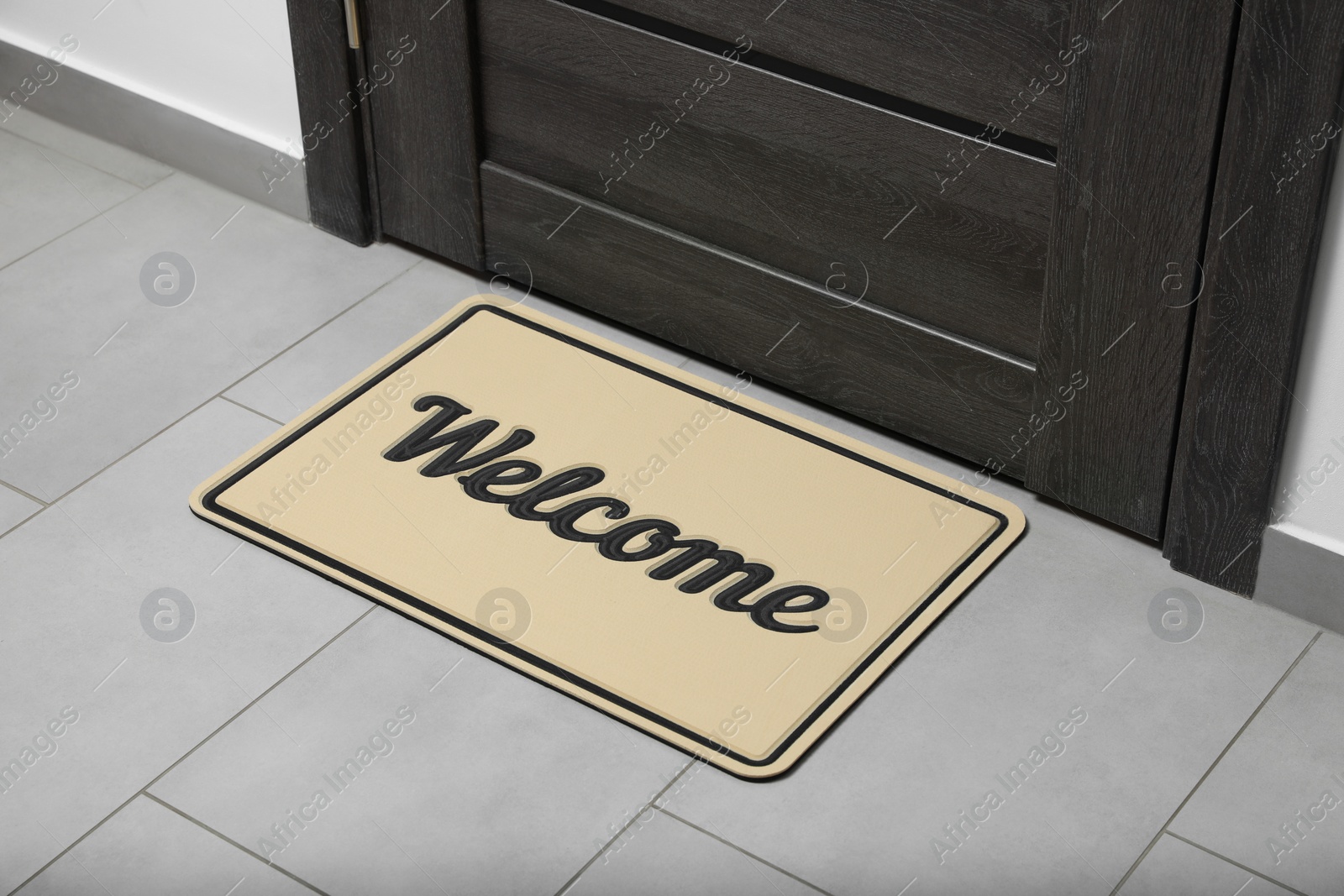 Photo of Beautiful beige doormat with word Welcome on floor near entrance