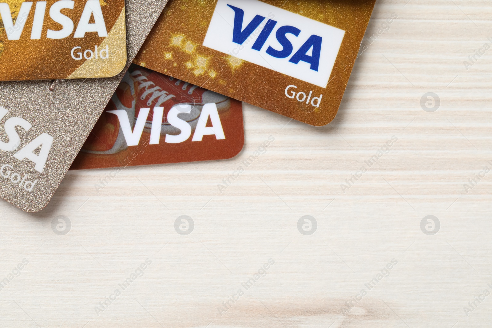 Photo of MYKOLAIV, UKRAINE - FEBRUARY 22, 2022: Visa credit cards on white wooden table, flat lay. Space for text