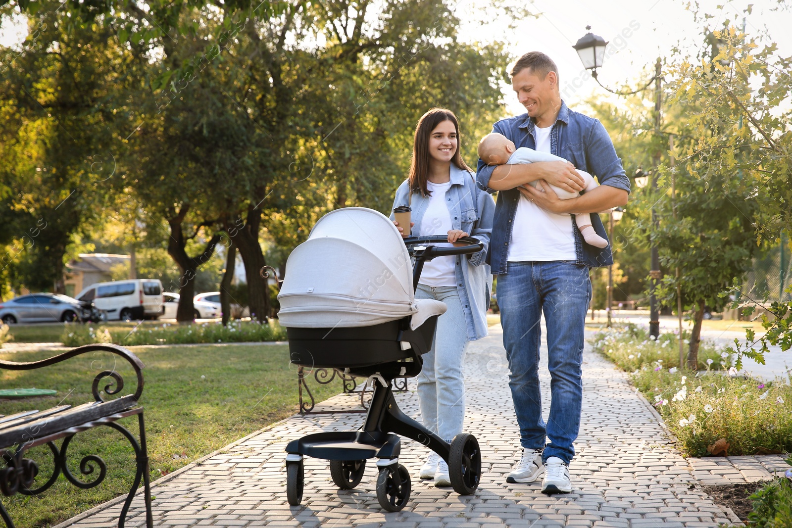 Photo of Happy parents walking with their baby in park on sunny day