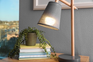 Photo of Books, lamp and beautiful plant on wooden table indoors. Interior elements