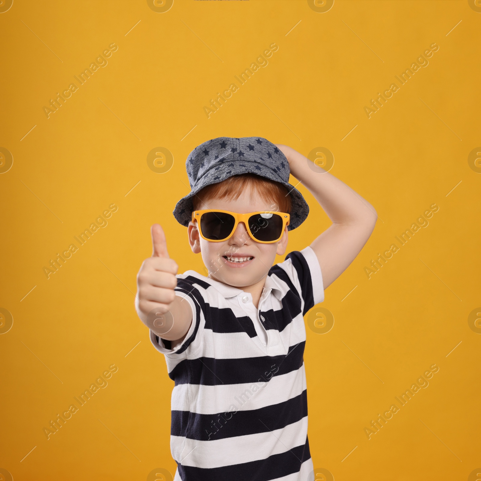 Photo of Cute little boy with sunglasses on yellow background