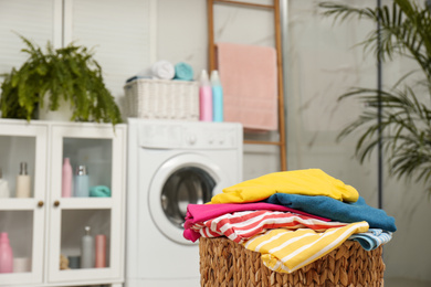 Wicker basket with laundry in bathroom. Space for text