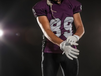 Photo of American football player wearing uniform on dark background, closeup