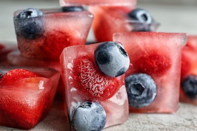 Photo of Ice cubes with berries on table, closeup