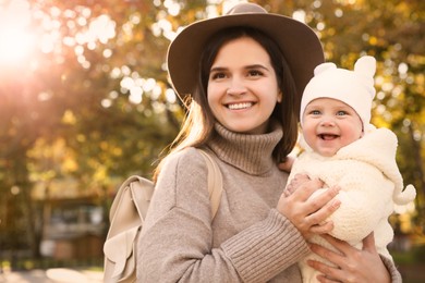 Happy mother with her baby daughter outdoors on autumn day