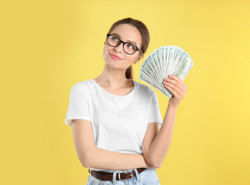 Photo of Young woman with money on yellow background. Space for text