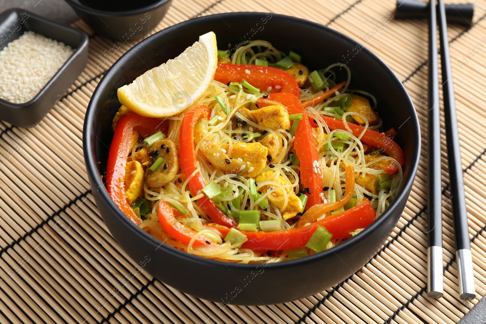 Photo of Stir-fry. Delicious cooked noodles with chicken and vegetables in bowl served on table, closeup